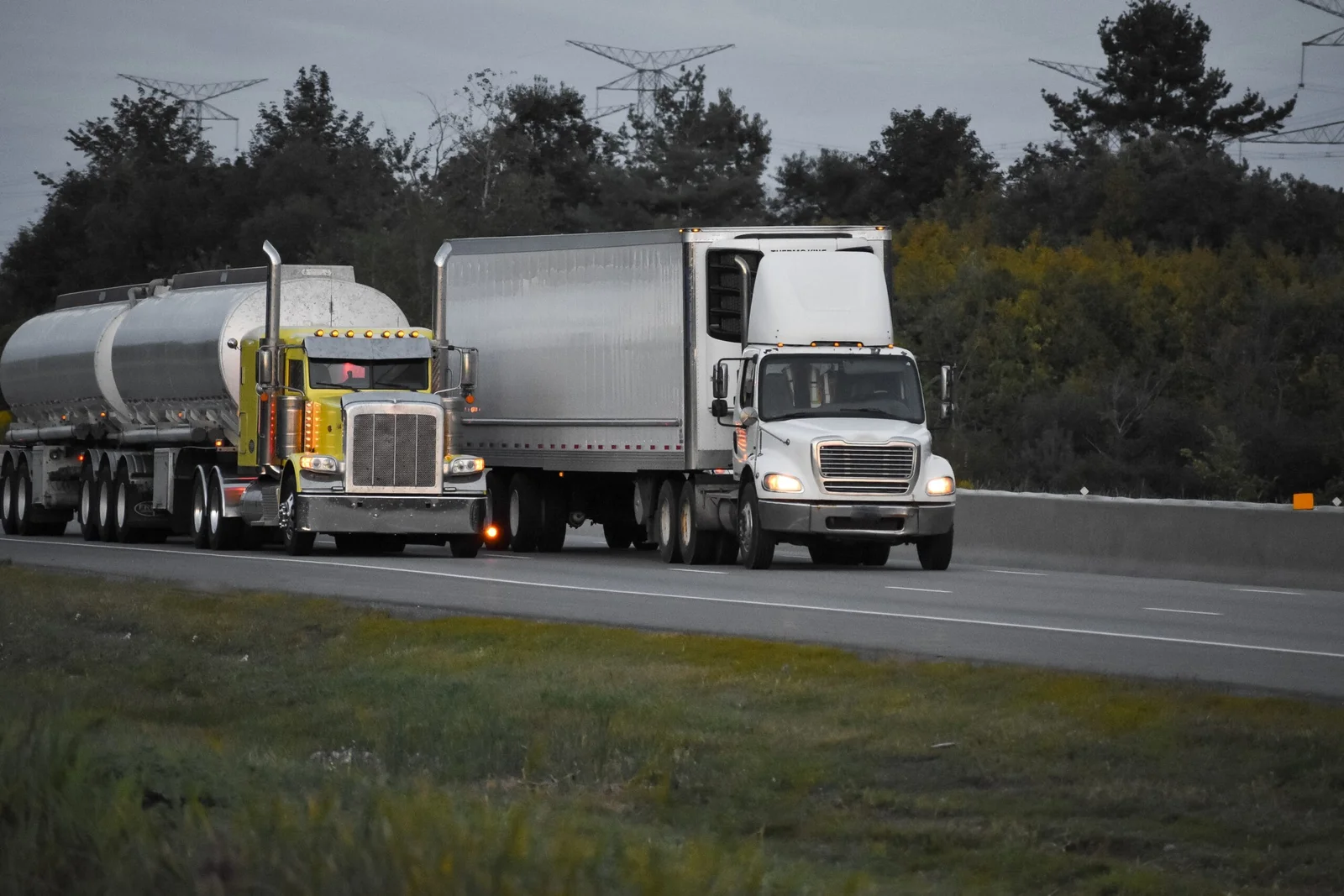 two semi trucks rolling down an interstate highway